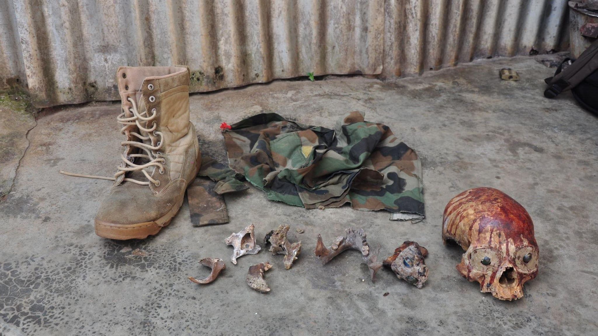 An image of military attire, small bones fragments and a bloody skull.