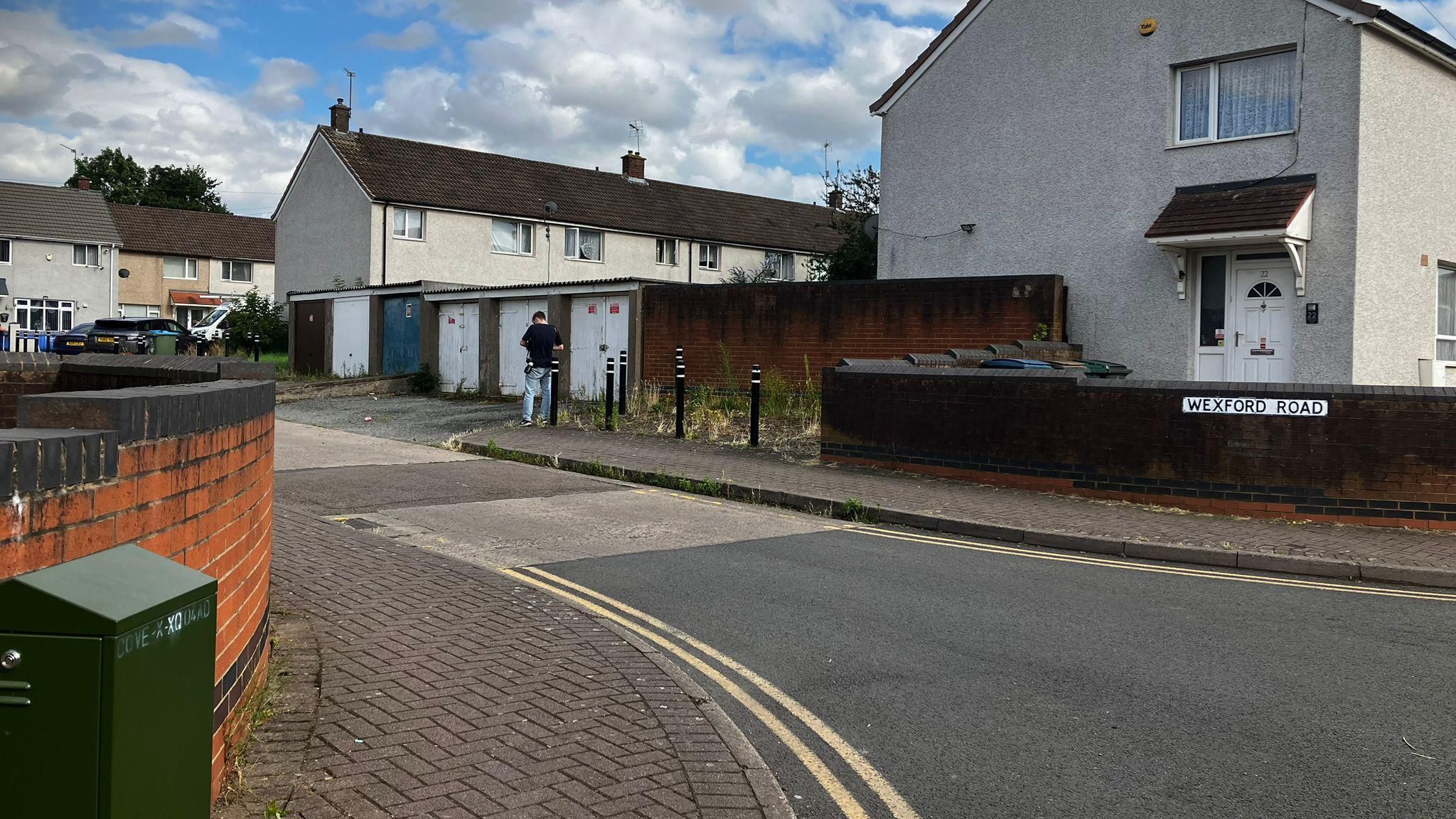 The junction of a road with houses and garages in view and a sign reading Wexford Road on a wall