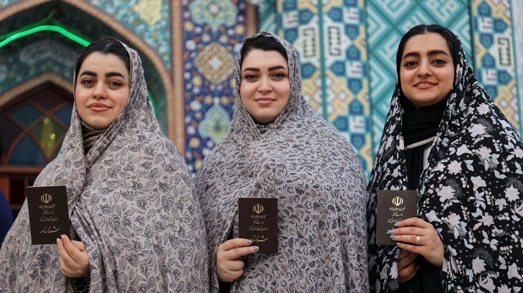 Three women holding their documents and smiling