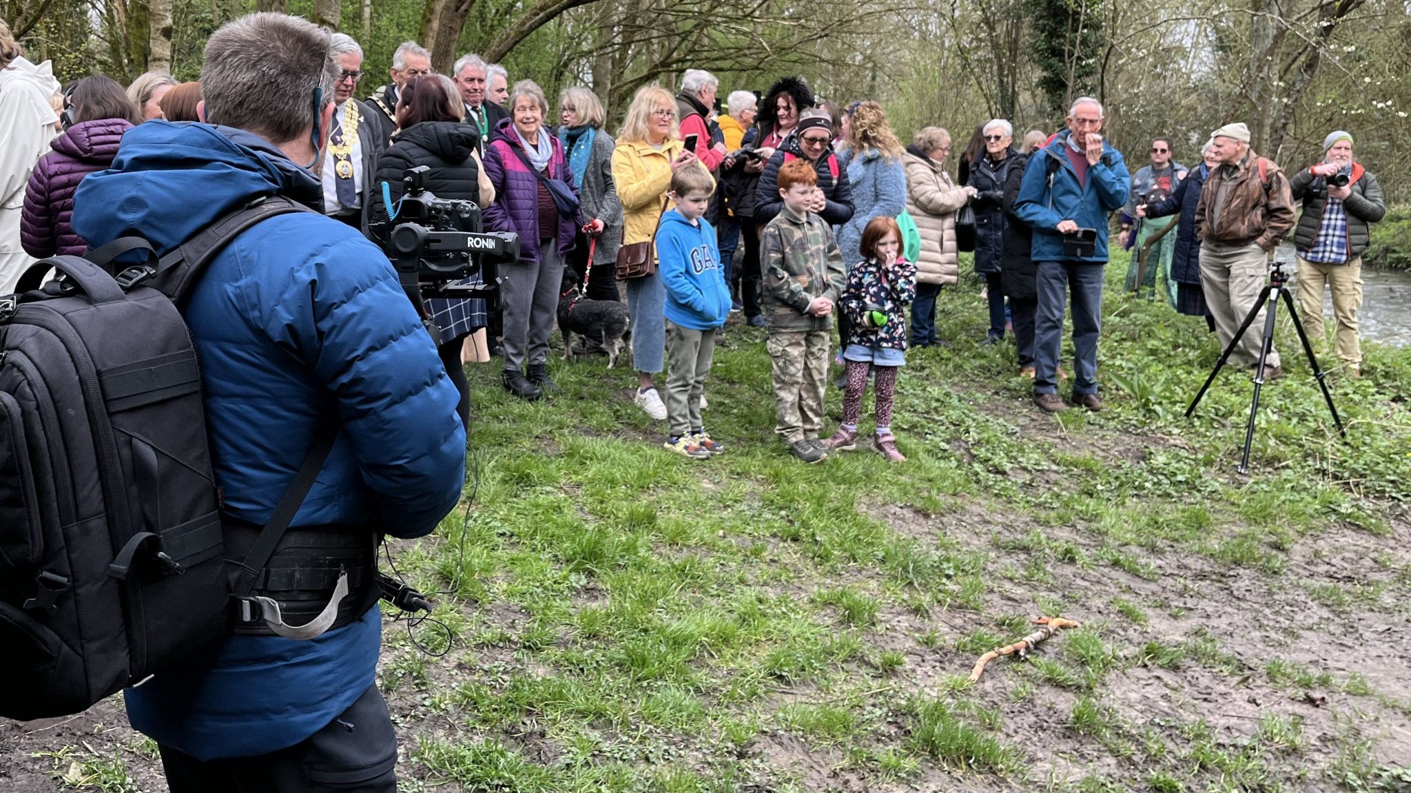Local people standing on the bank of the river Marden watching the blessing ceremony