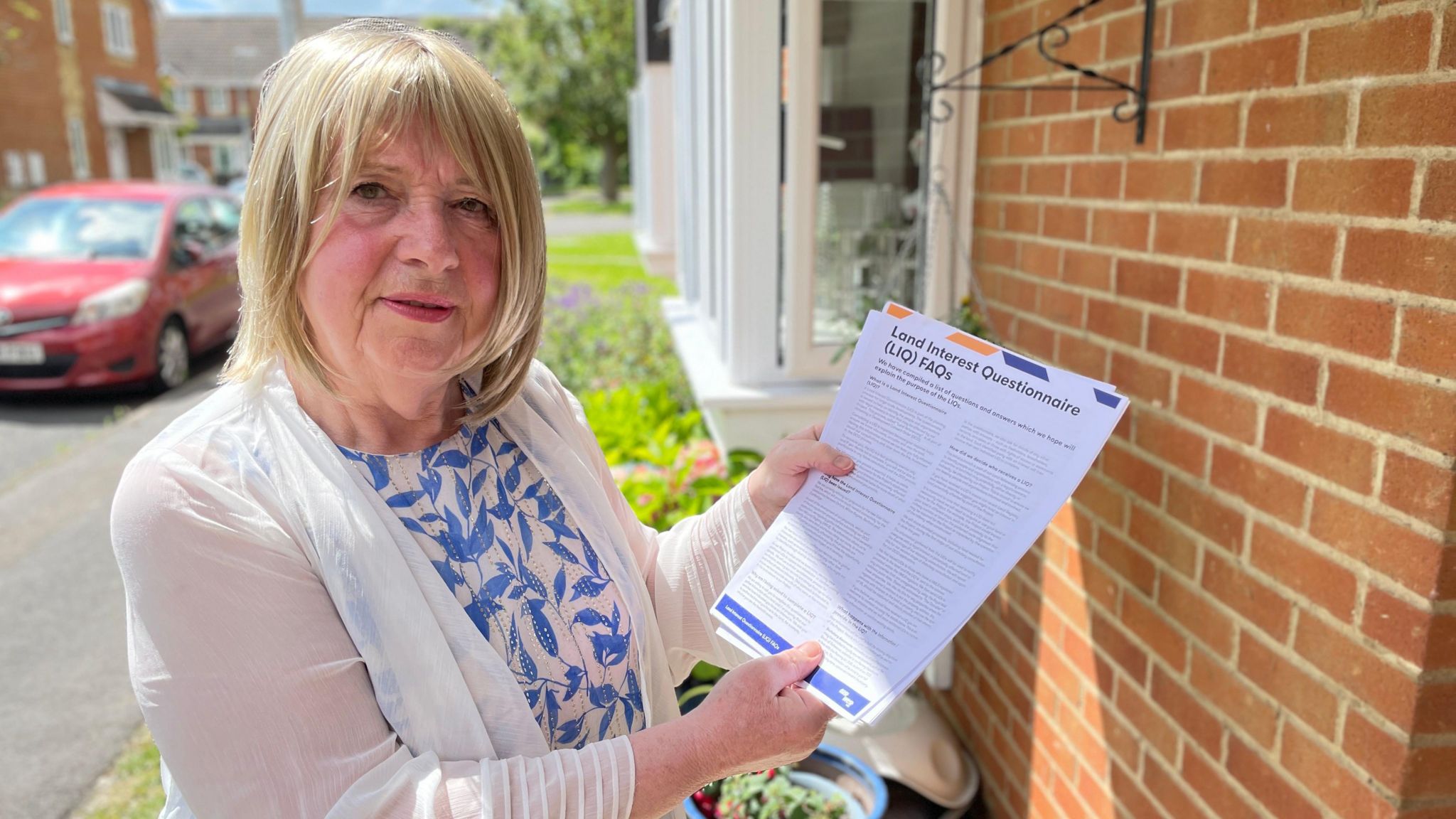 Elizabeth Swan holding a letter from East West Rail outside her property