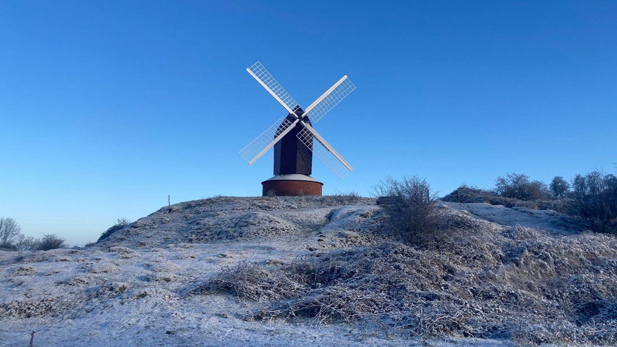 Brill Windmill standing on top of a frost covered hill on a bright blue day