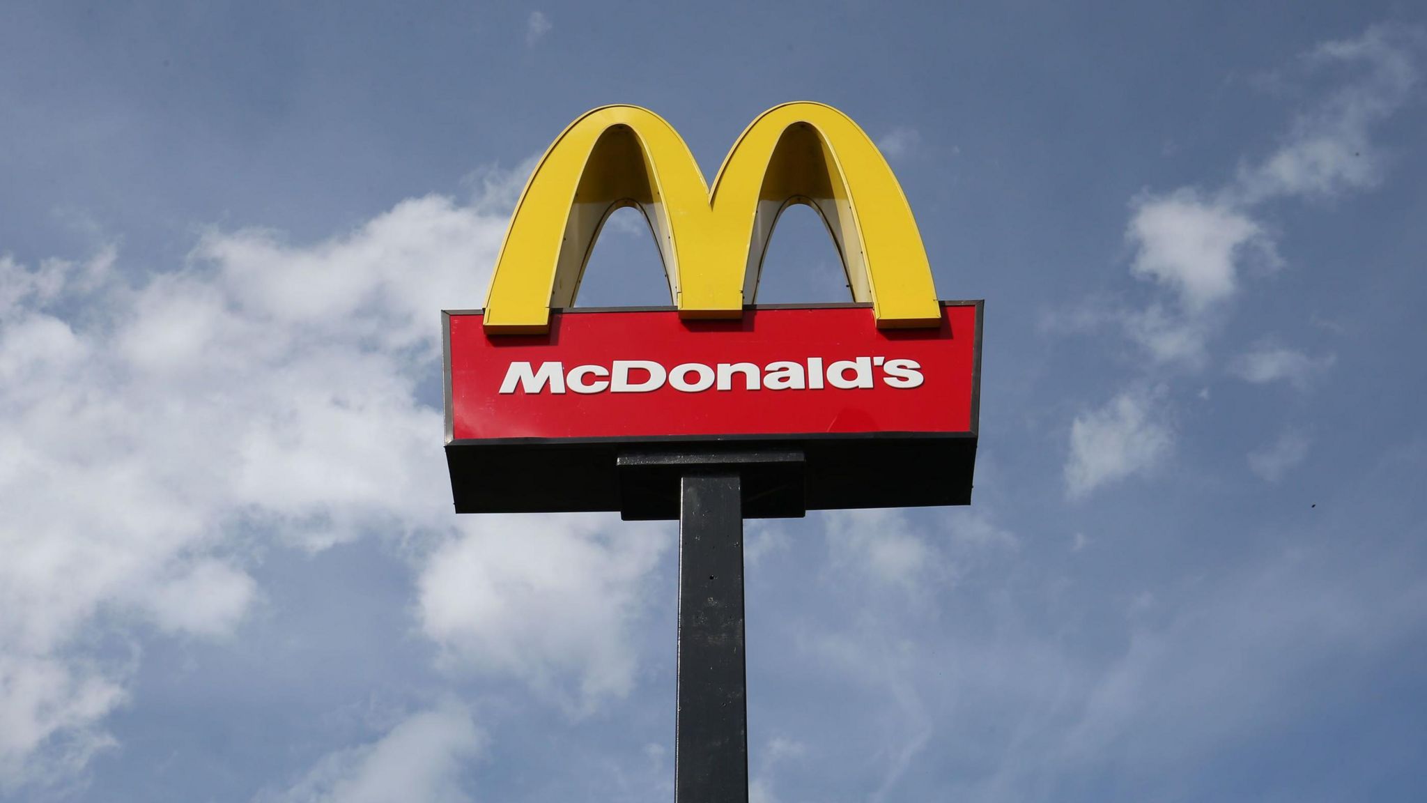 Upwards shot of McDonald's sign against a blue skie with a few white clouds