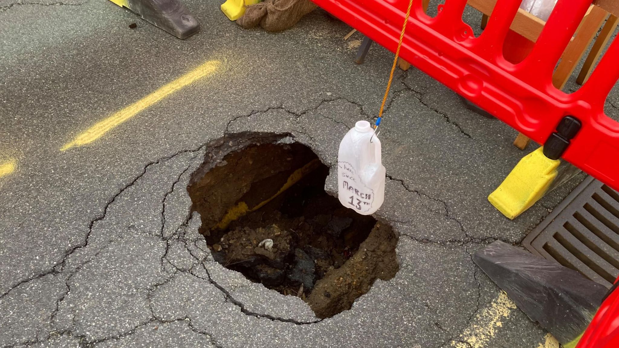 A sinkhole in the surface of High Street, Ipswich, with a plastic bottle dangling over it