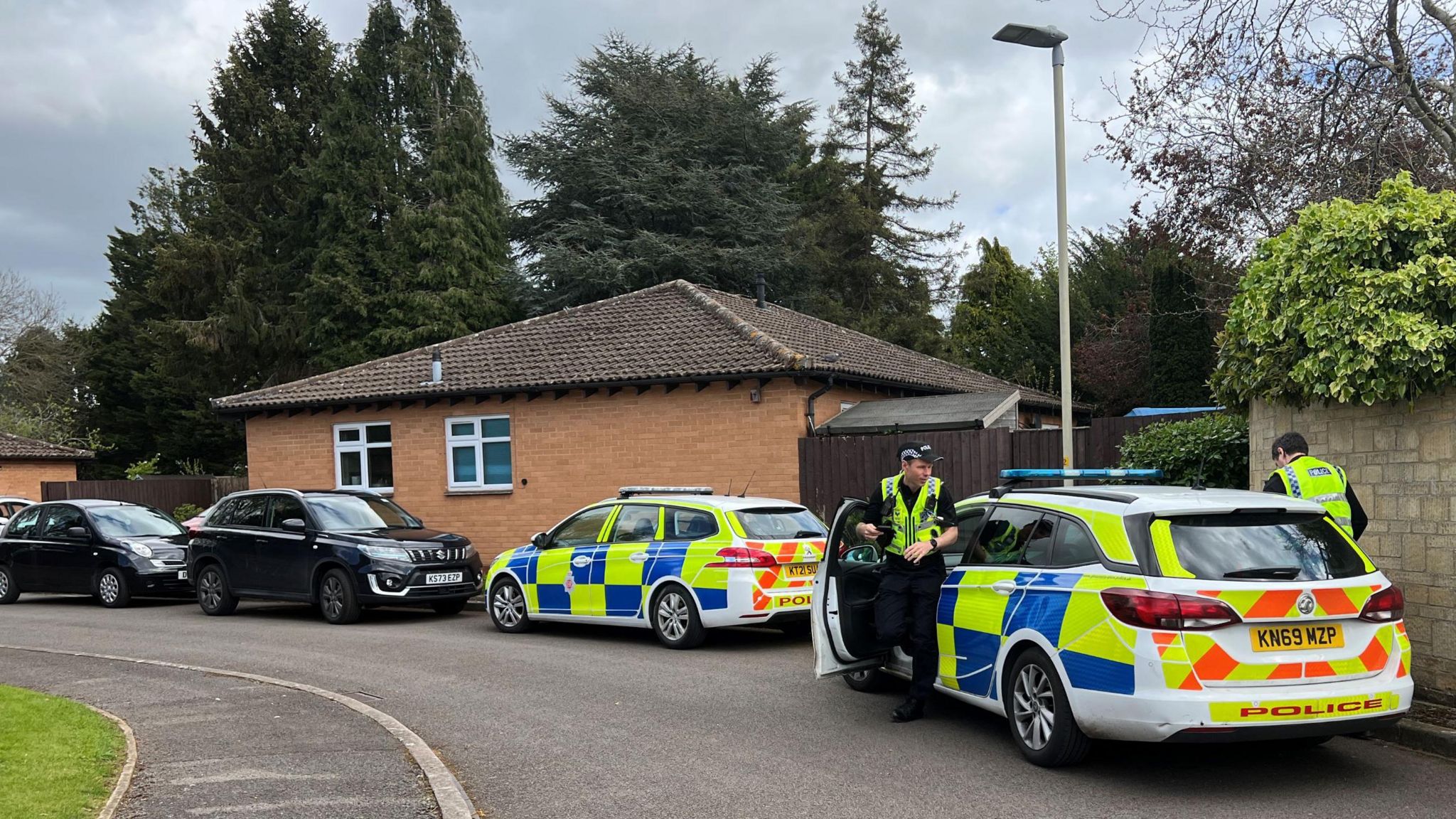 Police officers getting out of a car - there is another police car in front of them