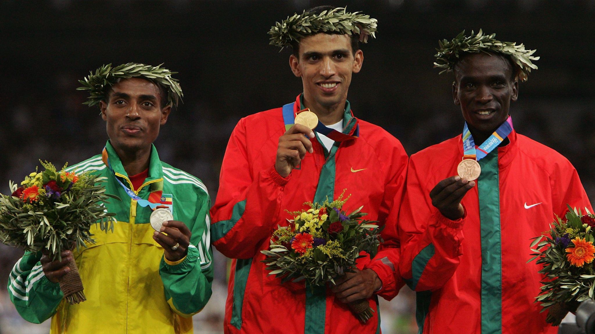 Gold medalist Hicham El Guerrouj of Morocco (centre), silver medallist Kenenisa Bekele of Ethiopia (left) and bronze medallist Eliud Kipchoge of Kenya (right) celebrate on the podium during the medal ceremony of the men's 5,000 metres at Athens 2004 