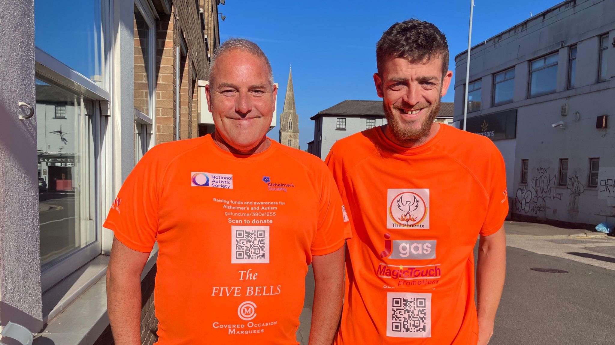 Innes Miles (L) and Jordan Brooks (R) in orange t-shirts standing, outside