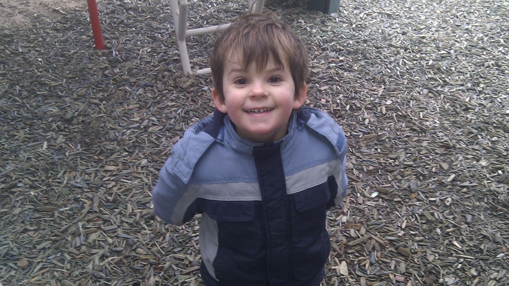 A young boy in a play area, smiling at the camera