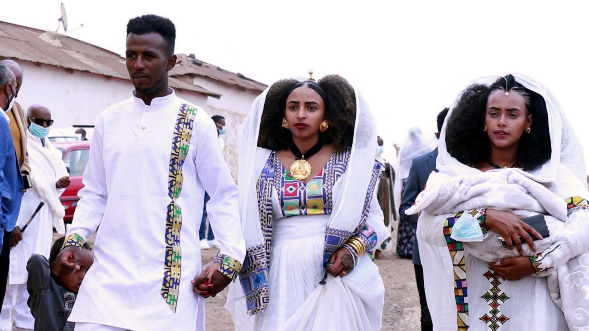 Biniam and his wife, Saliem, hold hands as his their baby daughter is carried beside them