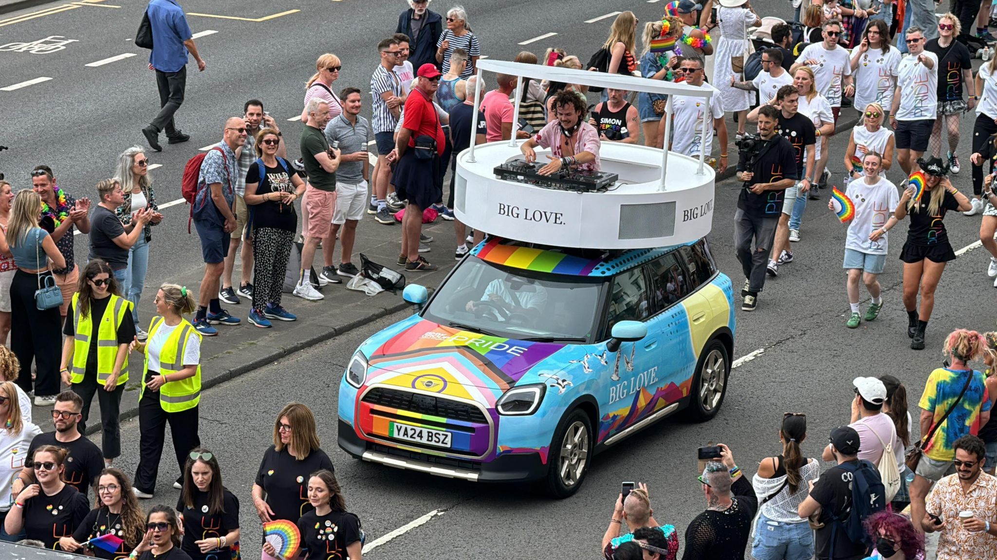 DJ Woody Cook on the roof of a rainbow Mini in the Brighton Pride parade