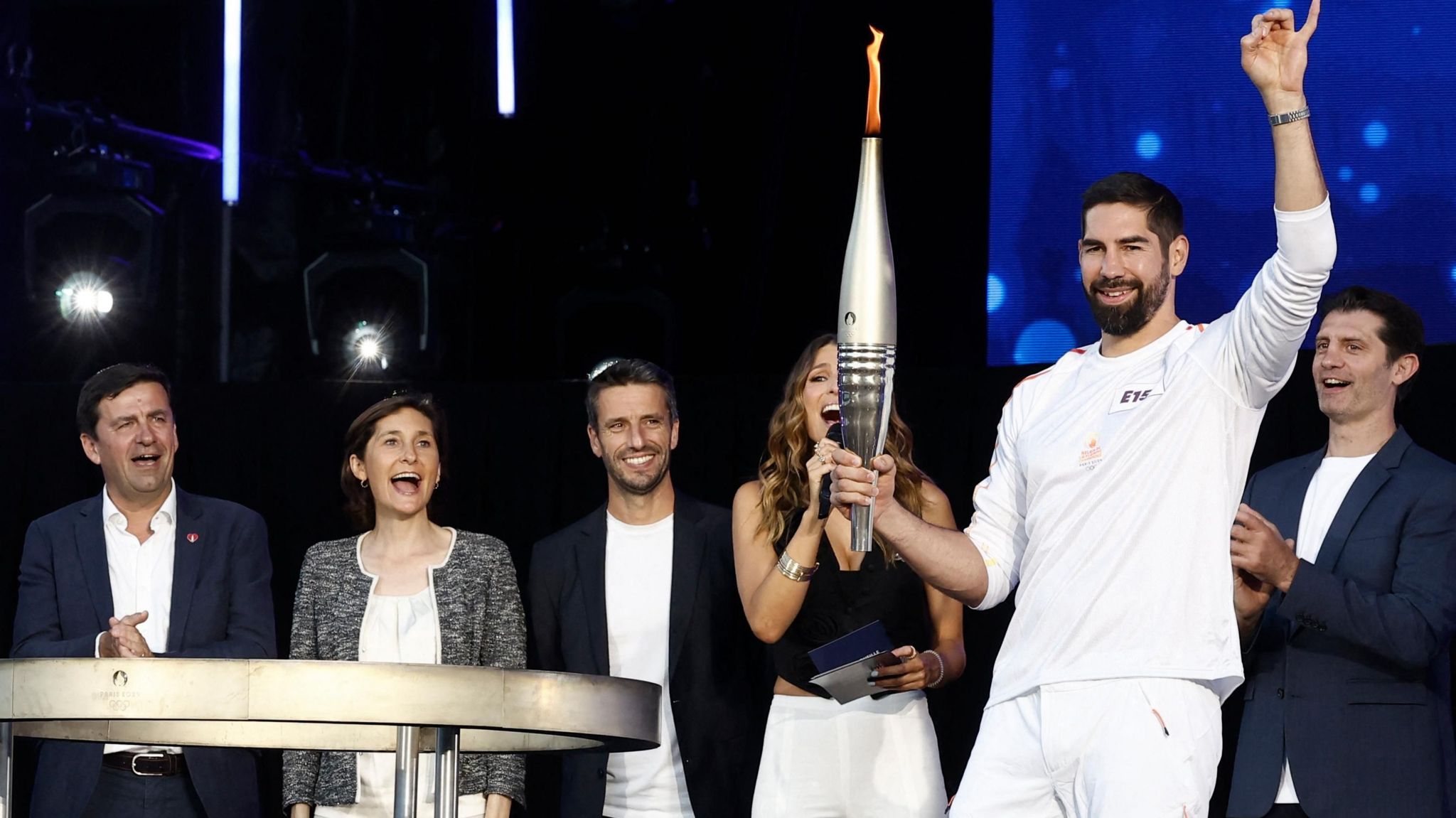 People clap and cheer as the 2024 Olympic torch is used to light the cauldron