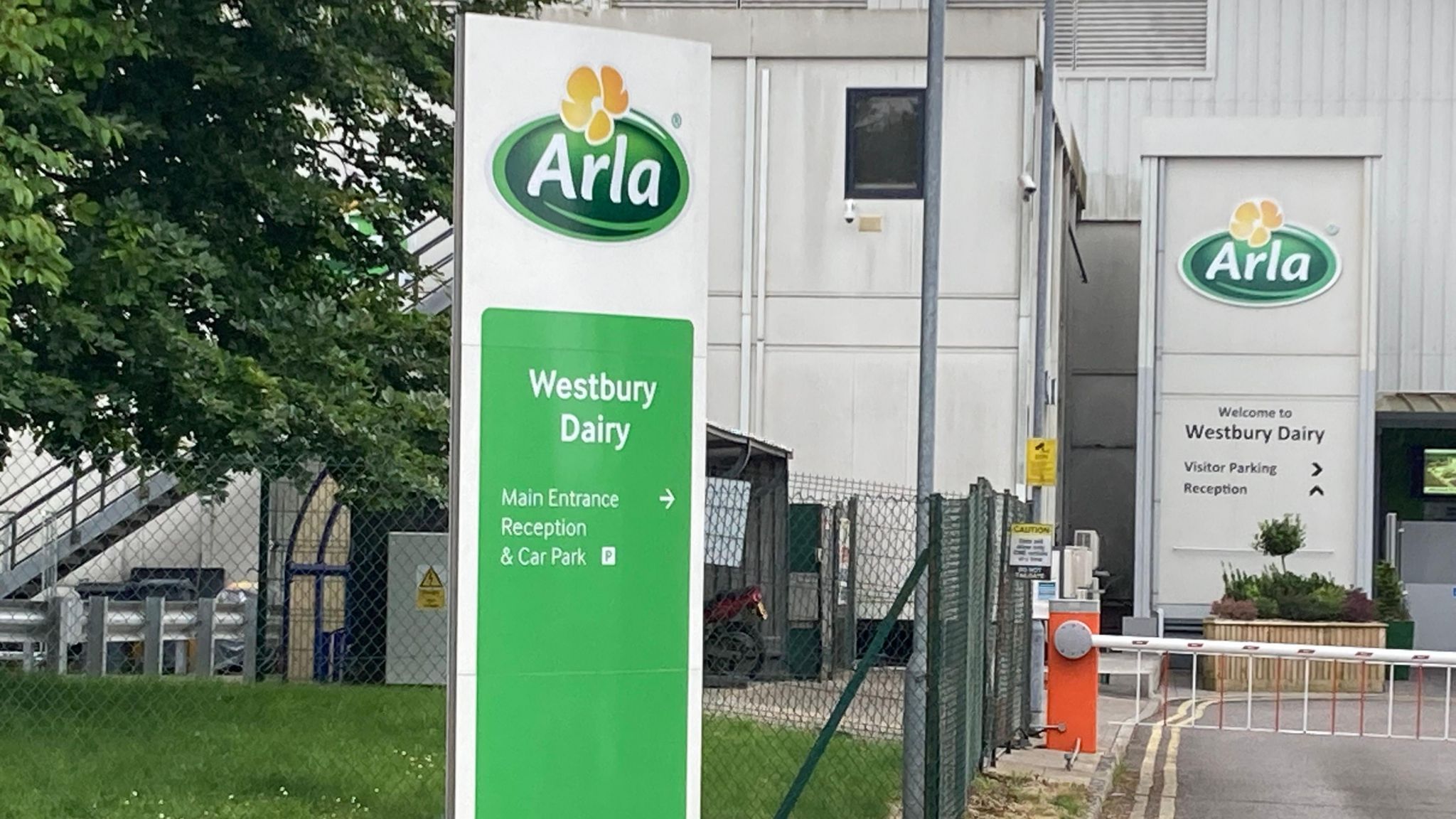 A green entry sign for Arla in front of a grey building on an industrial estate