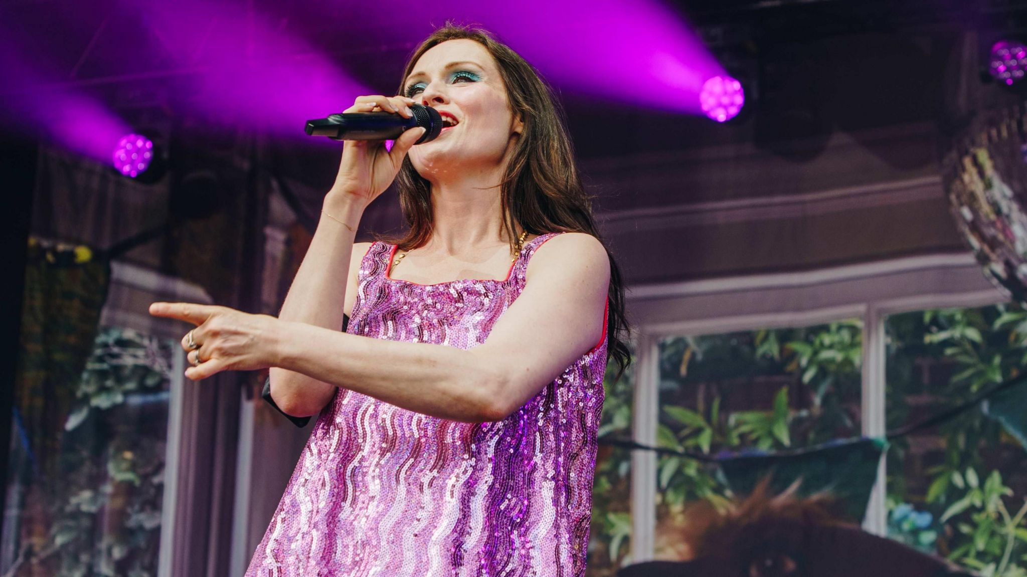 Sophie Ellis-Bextor singing on stage, wearing a purple dress.