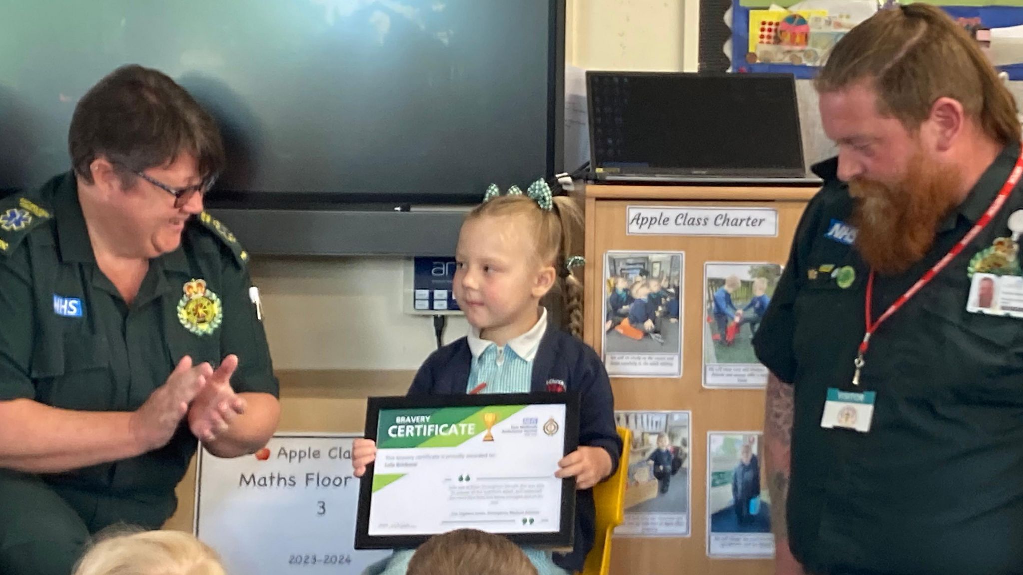 Lola being presented with her bravery award by paramedics