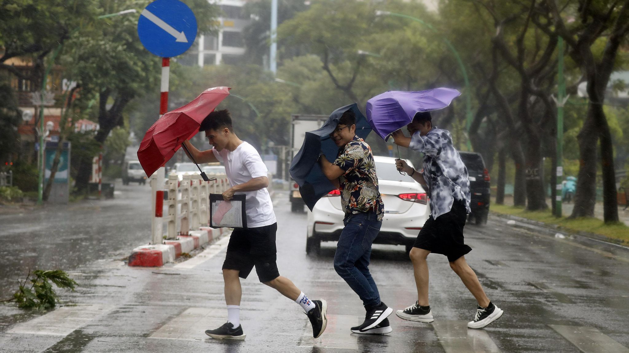 People hold umbrellas as they cross a street under the rain in Hanoi, Vietnam, 7 September 2024