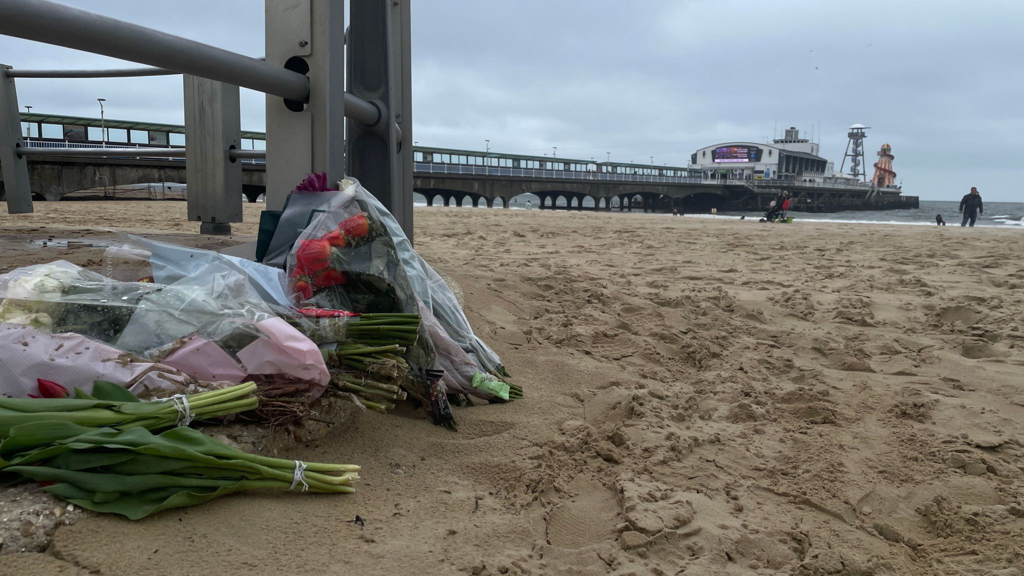 Flowers and tributes left on the beach, with Bournemouth pier in the background