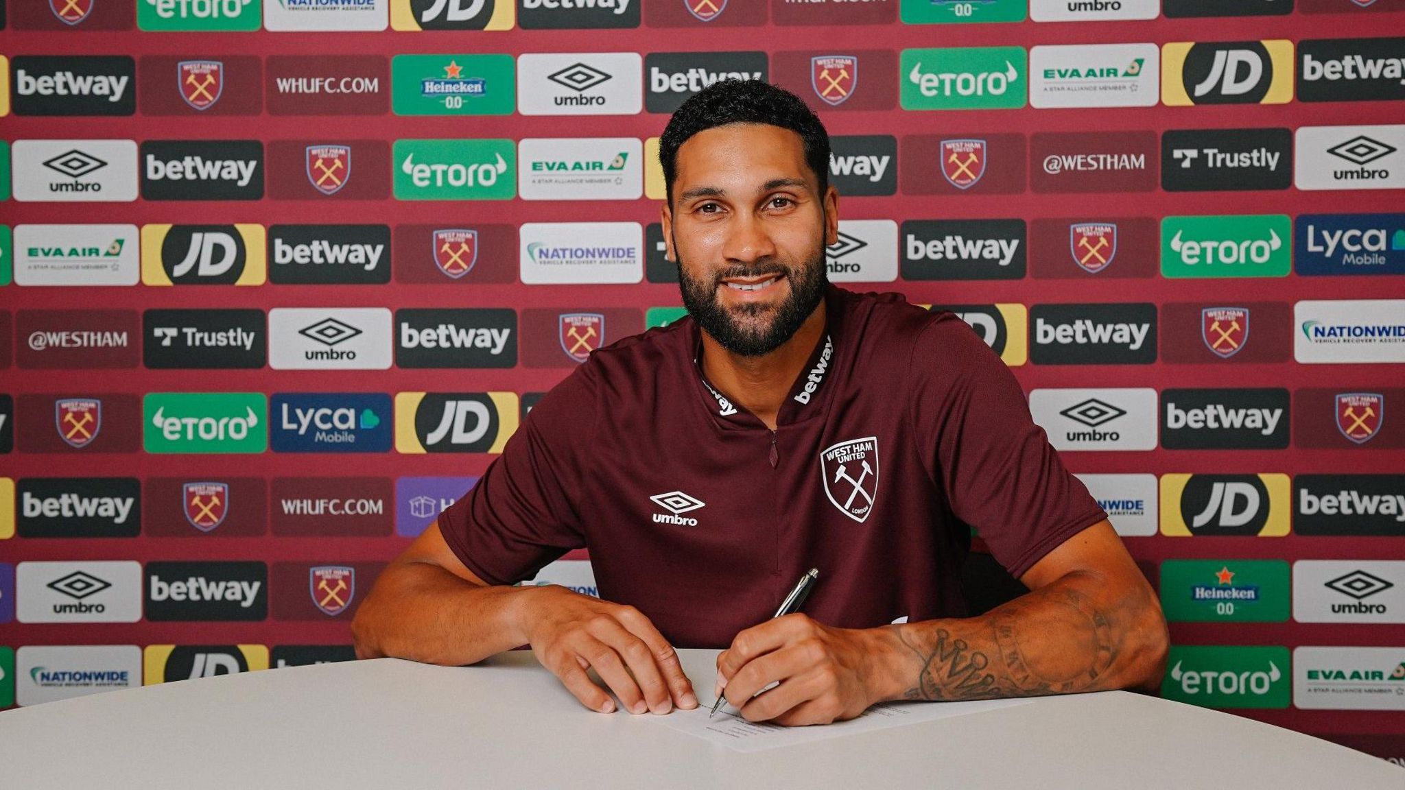Wes Foderingham sits at a table and signs a contract