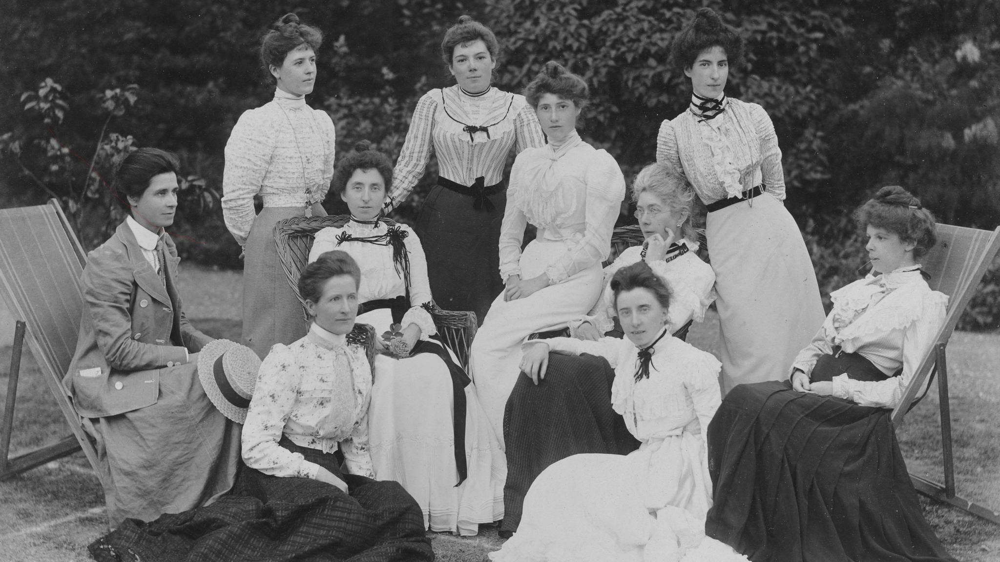 Black and white photo of ten women who trained to be physical education teachers in Bedford dressed in late-Edwardian formal dresses. 