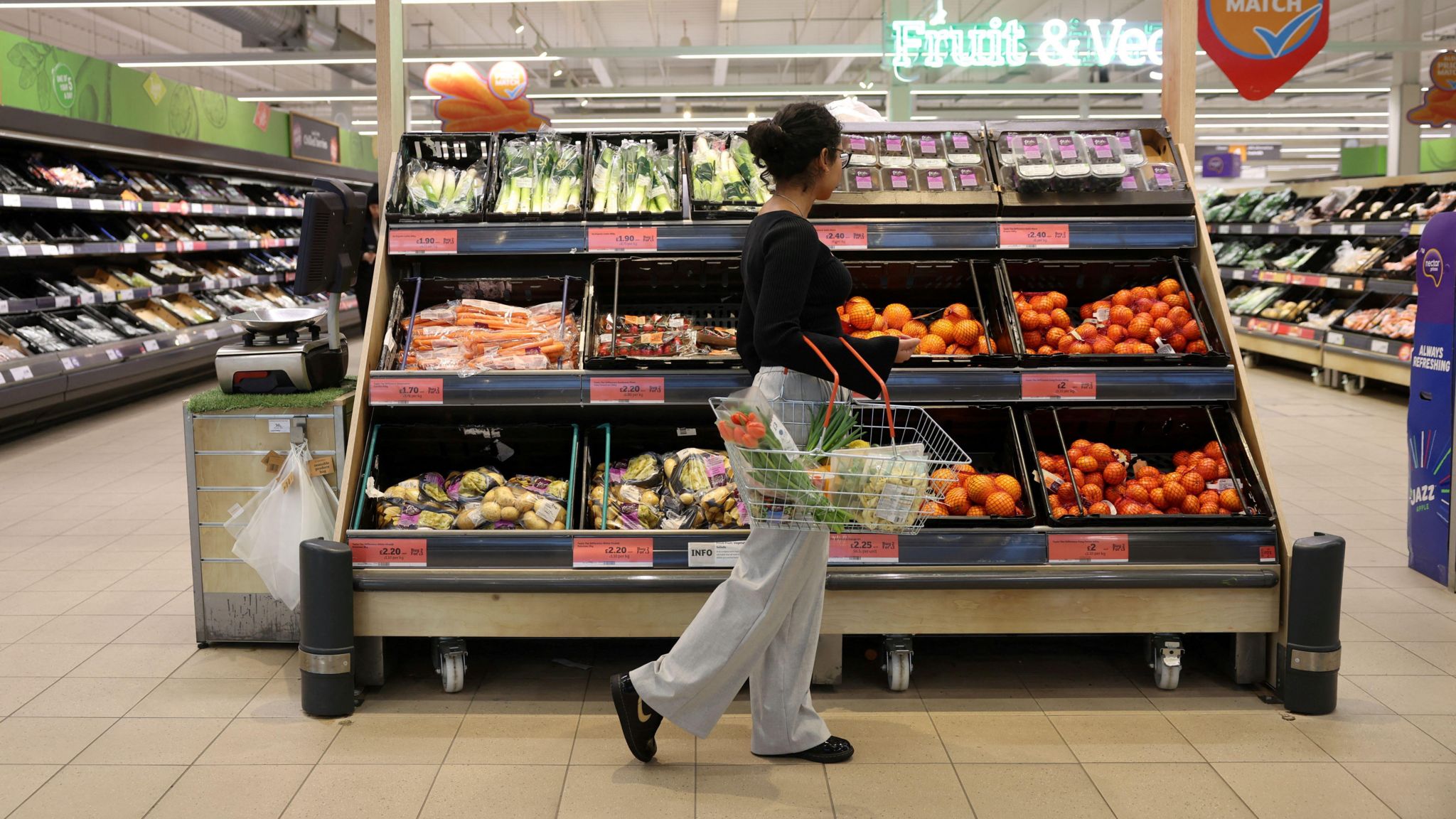 A customer shops in the fruit aisle inside a supermarket