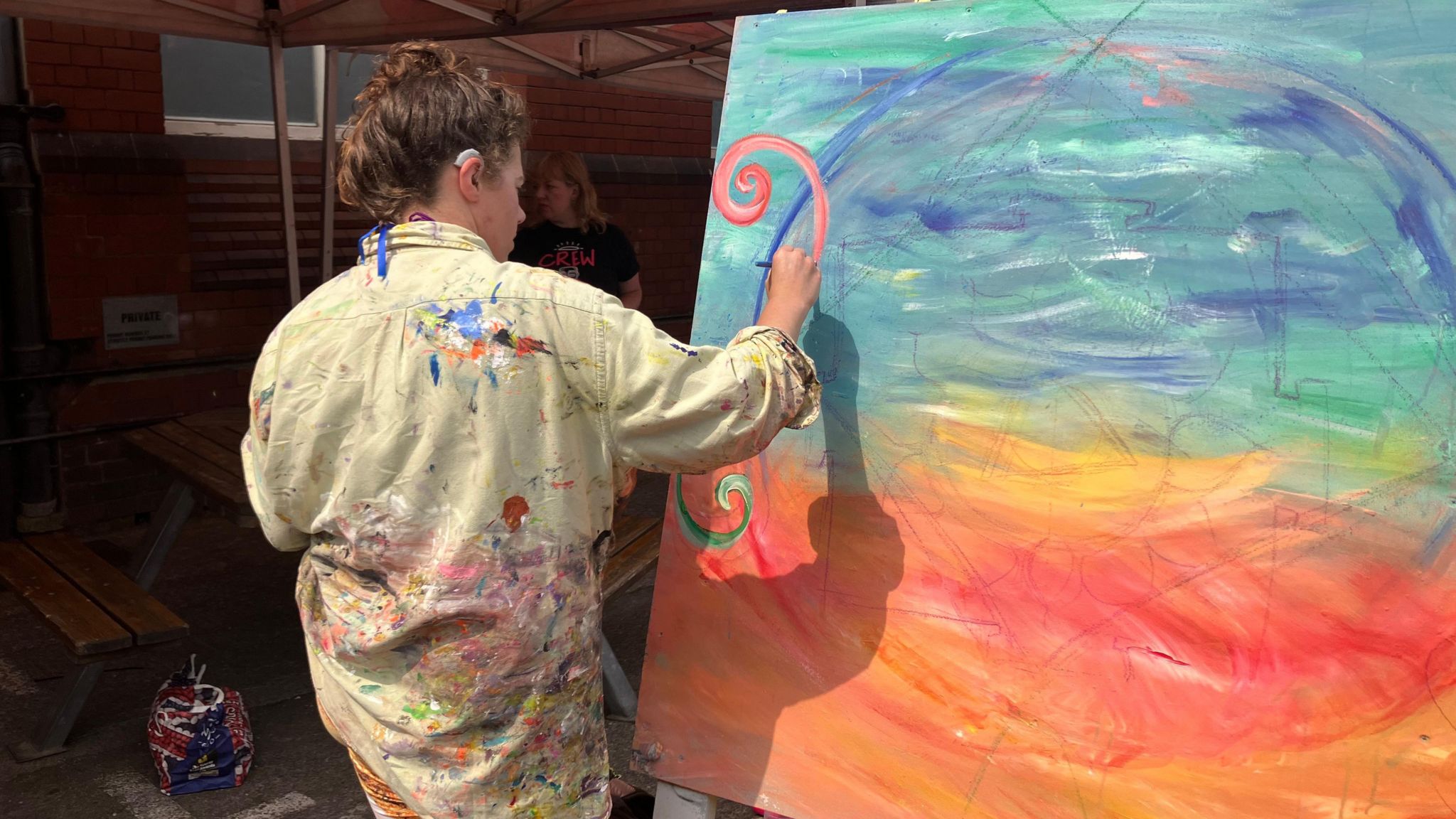 An artist painting on an orange and blue green canvas