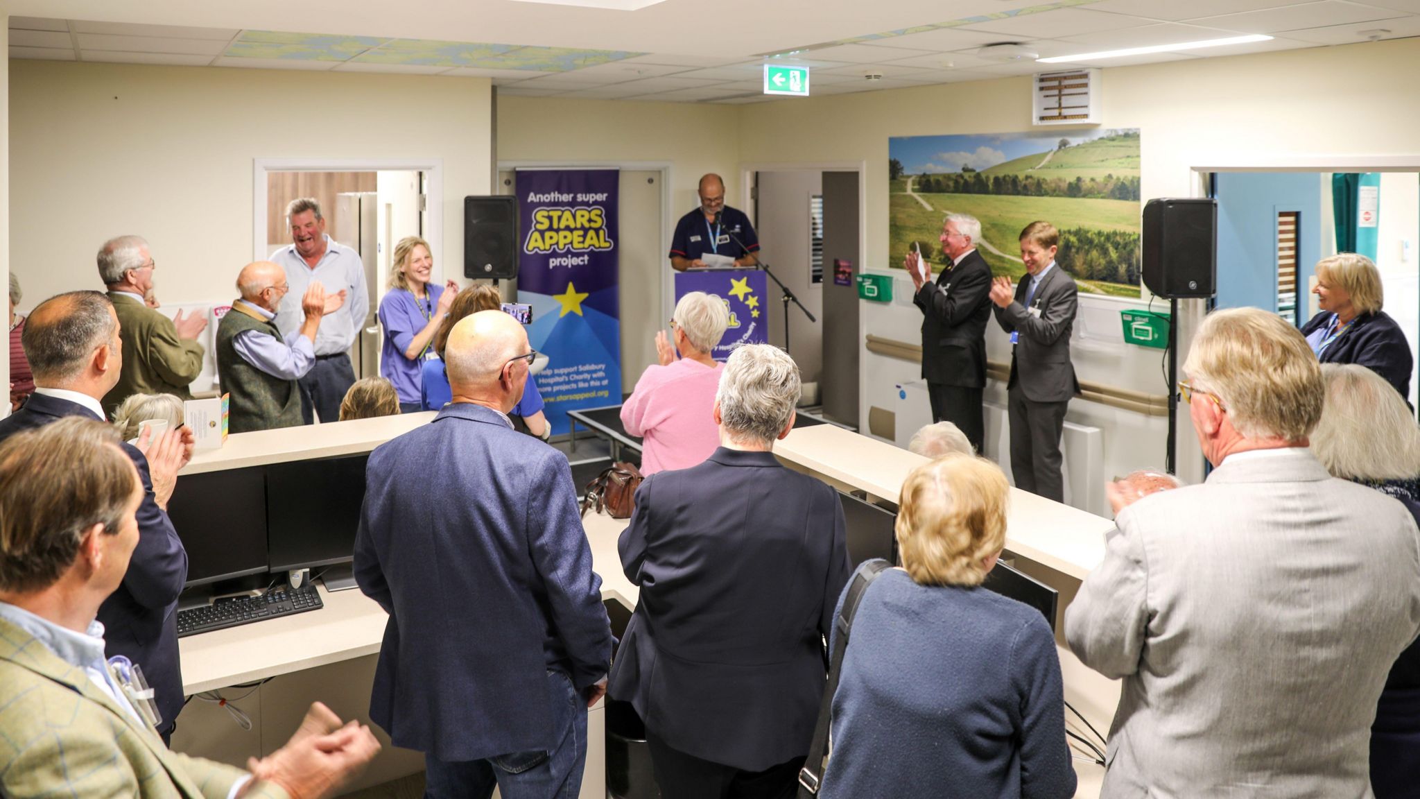 Small crowd in a office or classroom space listening to a speaker