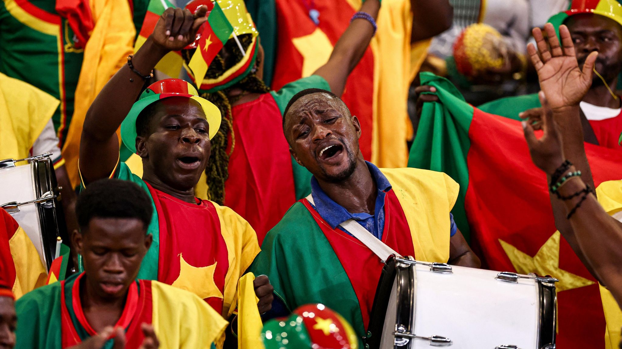 Cameroon fans hold out their hands in the stands of a football stadium
