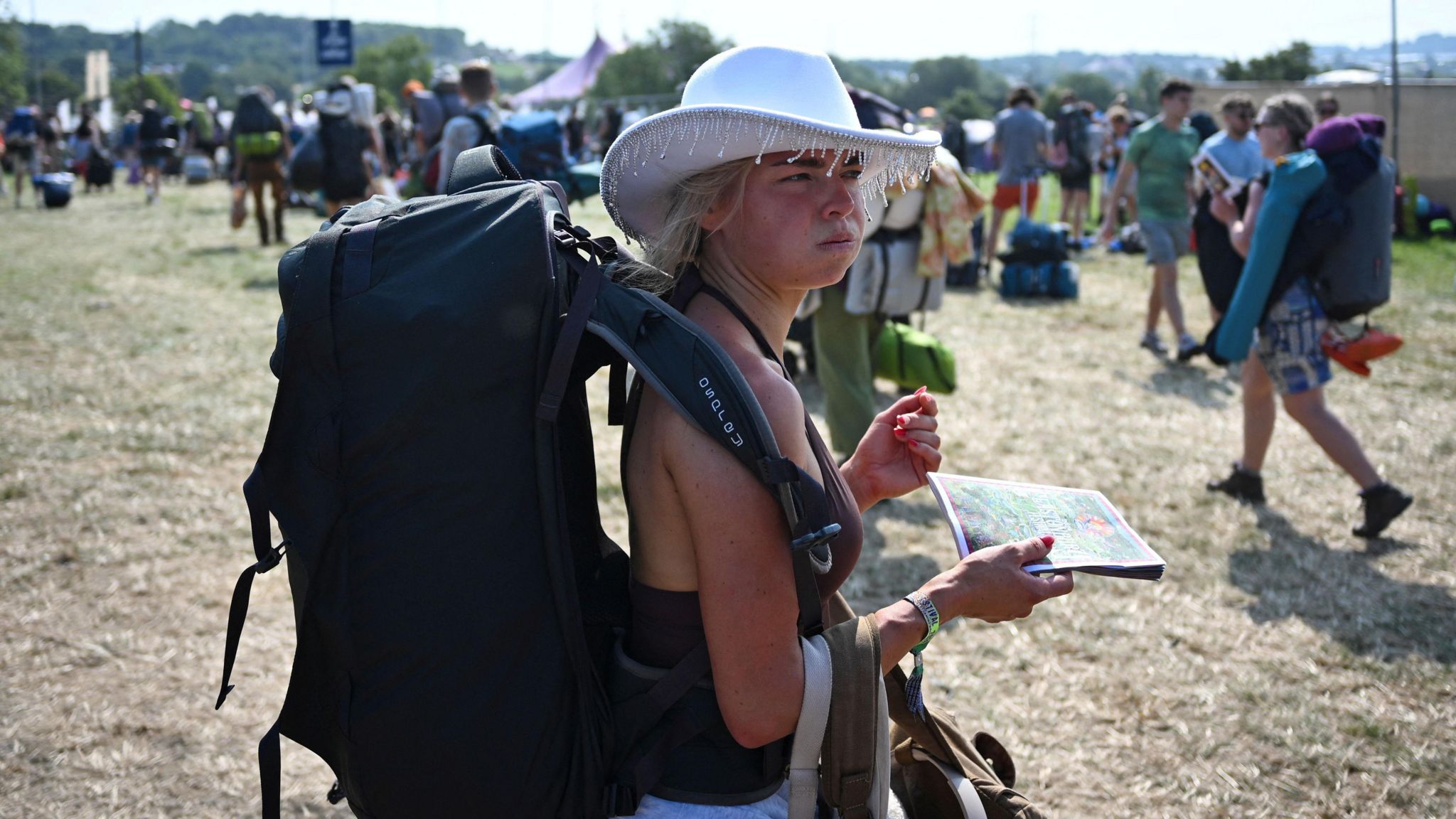 Woman arriving at Glastonbury with a large rucksack and a cowboy hat