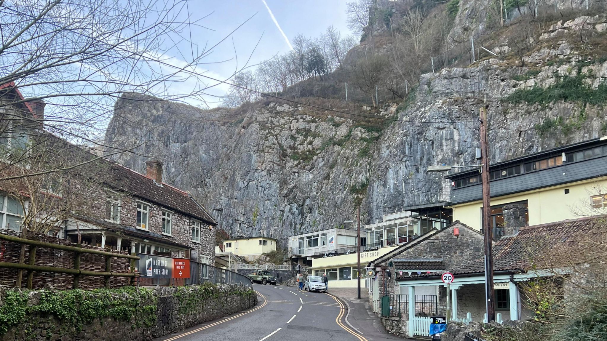 The road through Cheddar Gorge's cliffs with shops and homes near the road.