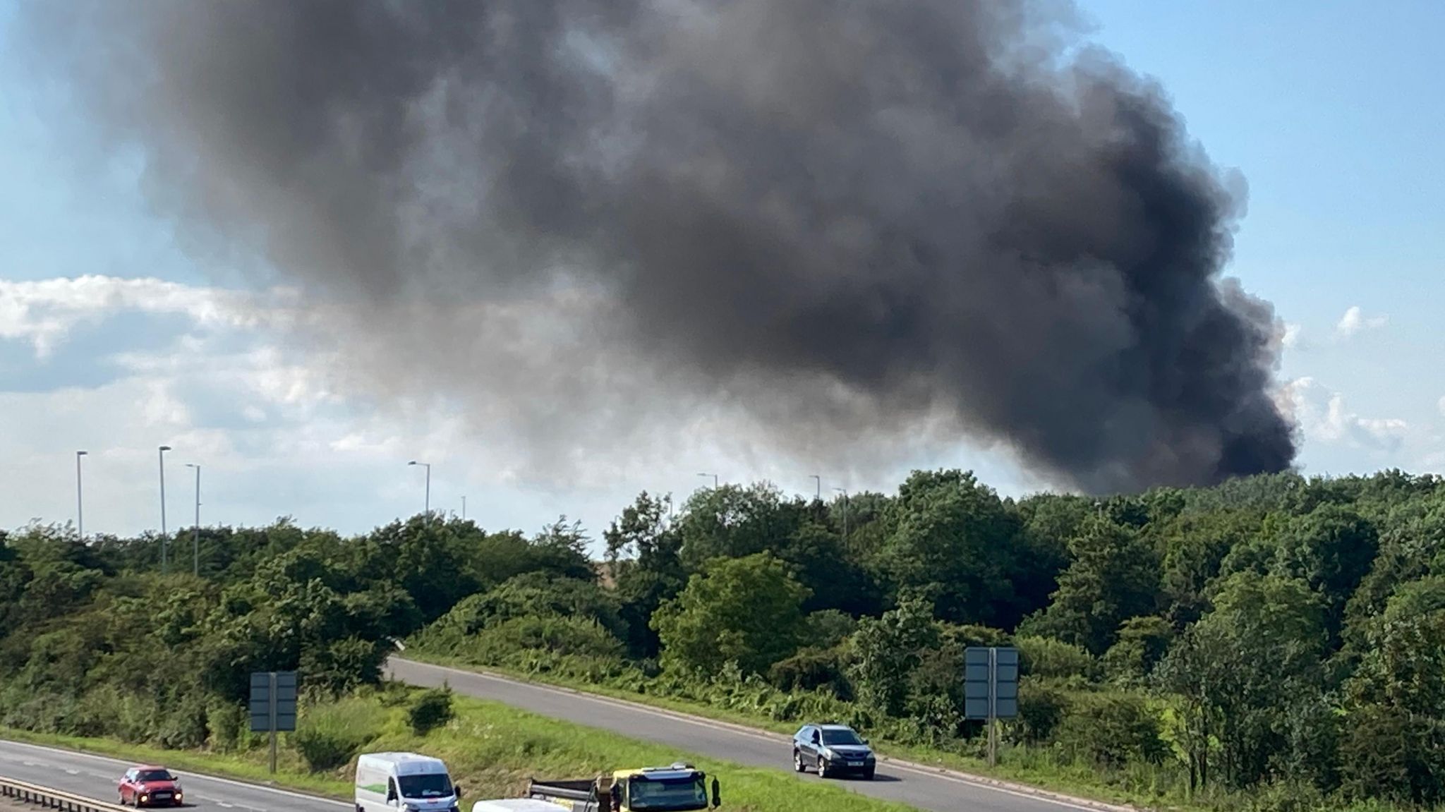 Large plume of black smoke rising above trees on the edge of the A14 near Milton, Cambridgeshire