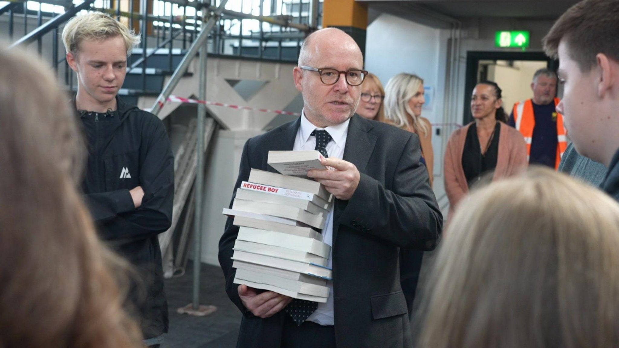 Attorney General Richard Hermer holding a stack of books in Spellow Library