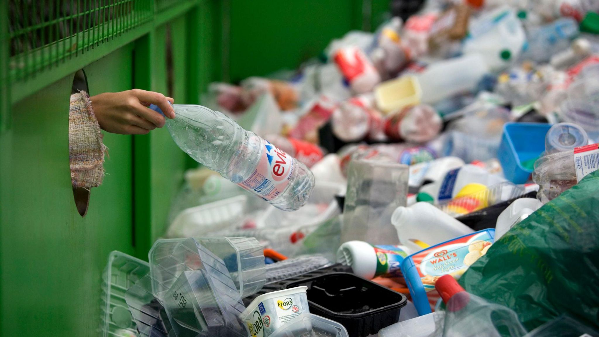 Person putting bottle into pile of plastic recycling