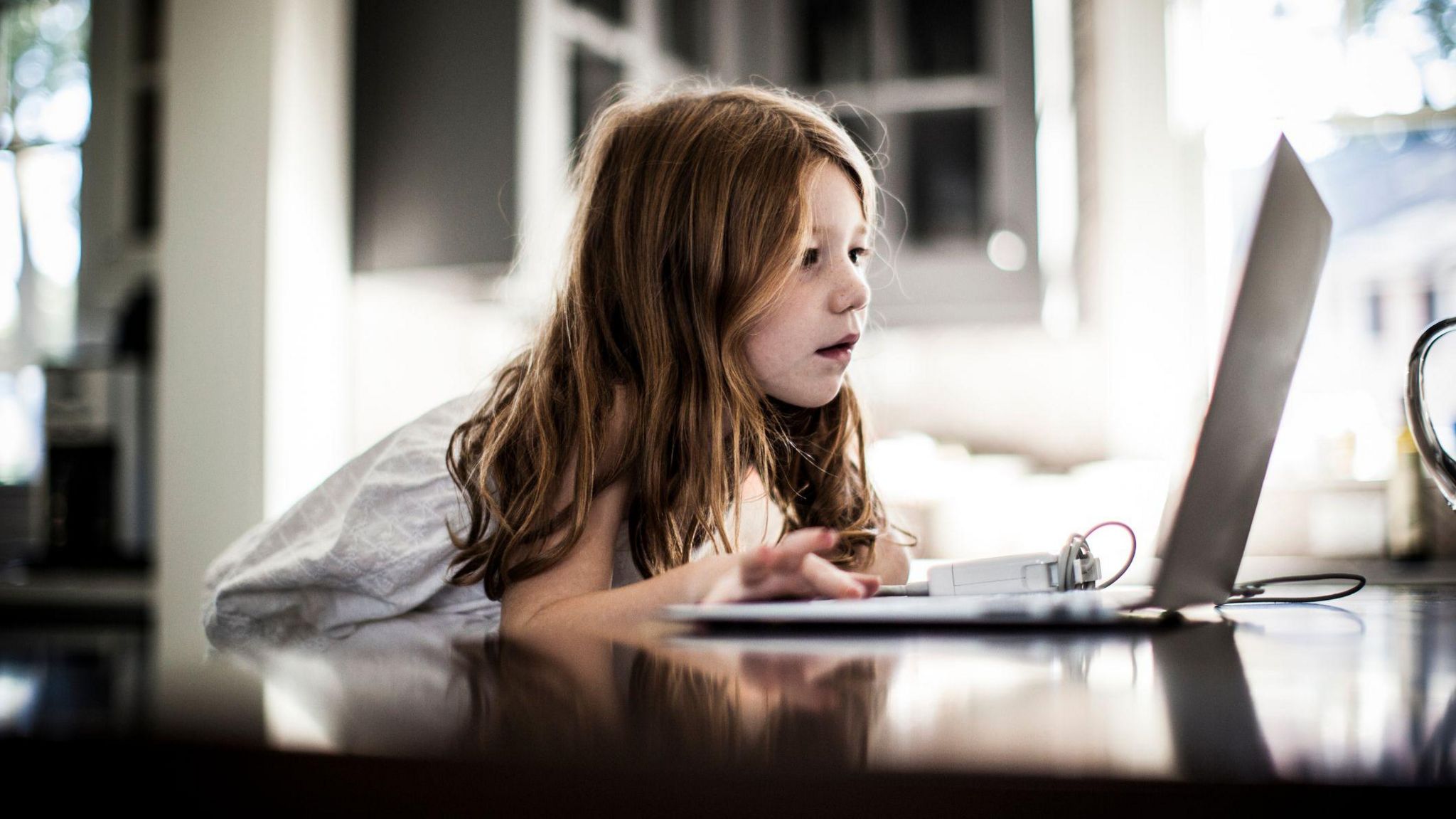 Young girl sits looking at a laptop screen