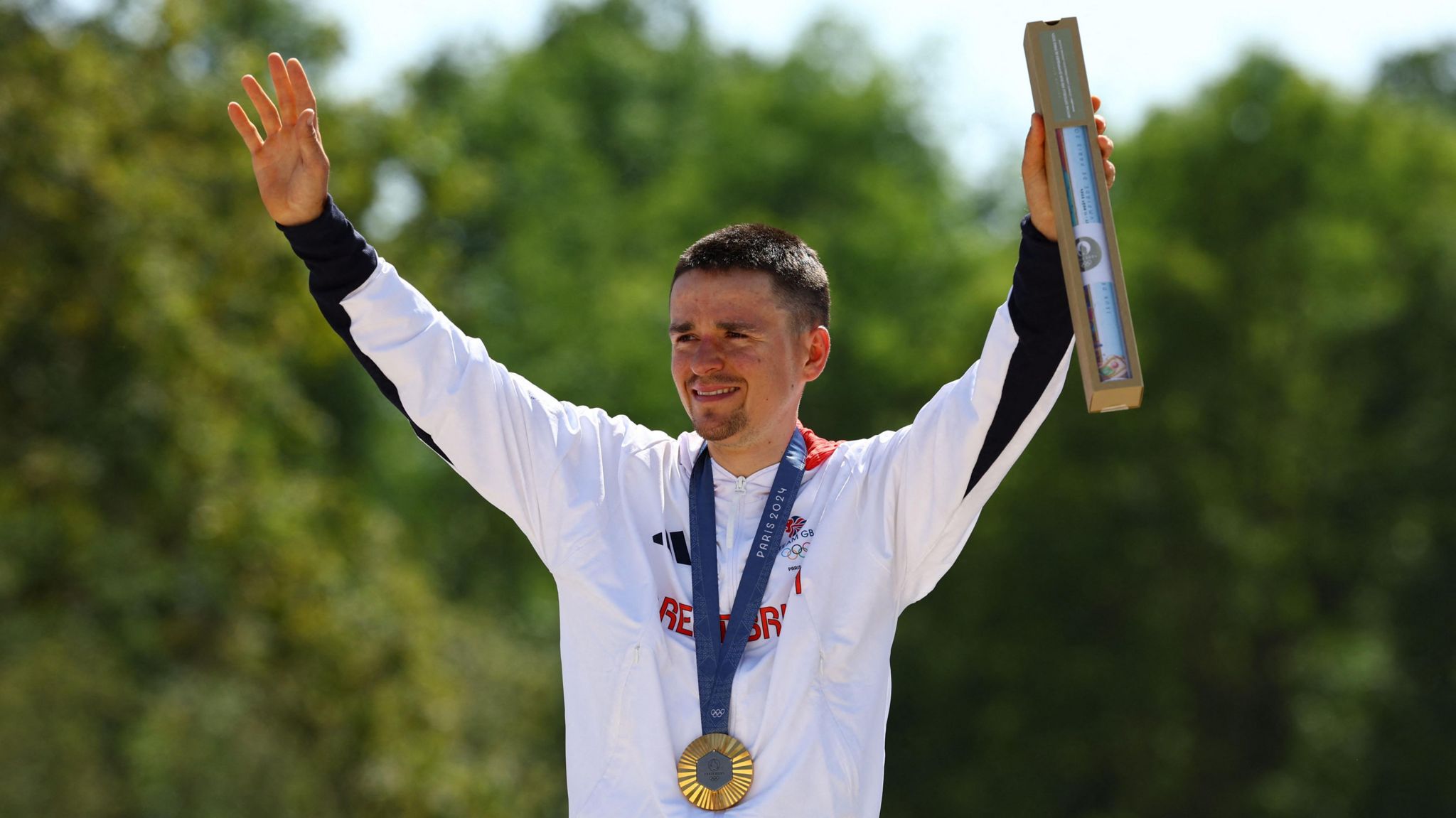 Thomas Pidcock celebrates his win, wearing the medal around his neck and raising his arms in the air in victory