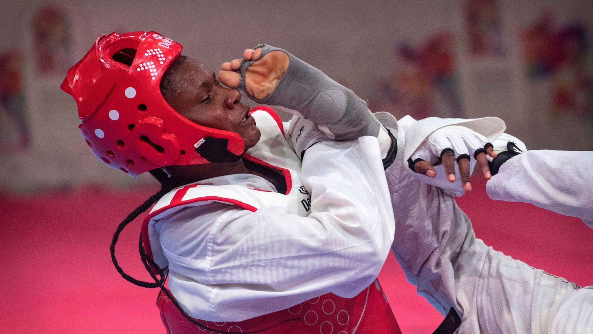 Faith Ogallo leans back with her opponent's toes on the brink of her nose as she fends off a kick in a taekwondo match