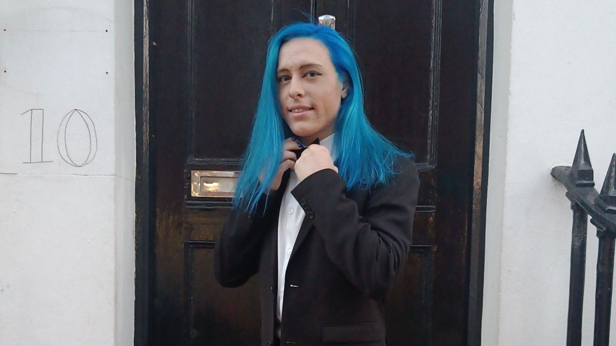Aqua has blue hair and wears a black suit jacket over a white shirt