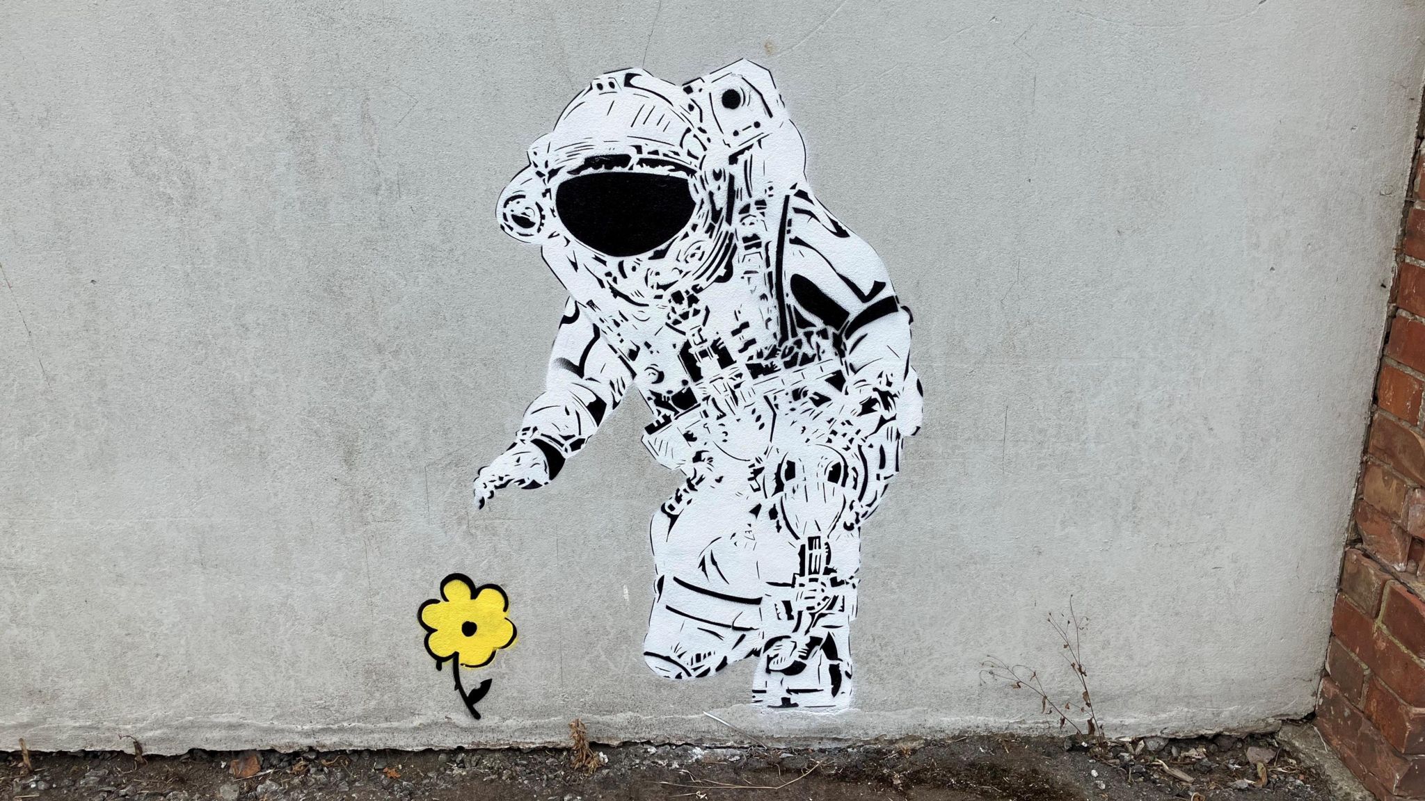 Painting with spaceman reaching down to pick up a yellow flower painted onto a wall