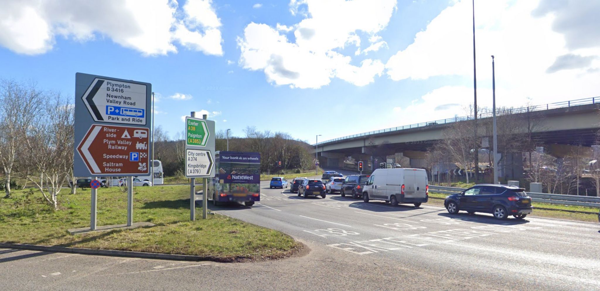 A roundabout under a flyover, with signs to Exeter, Paignton and Plympton as well as Plymouth City Centre.