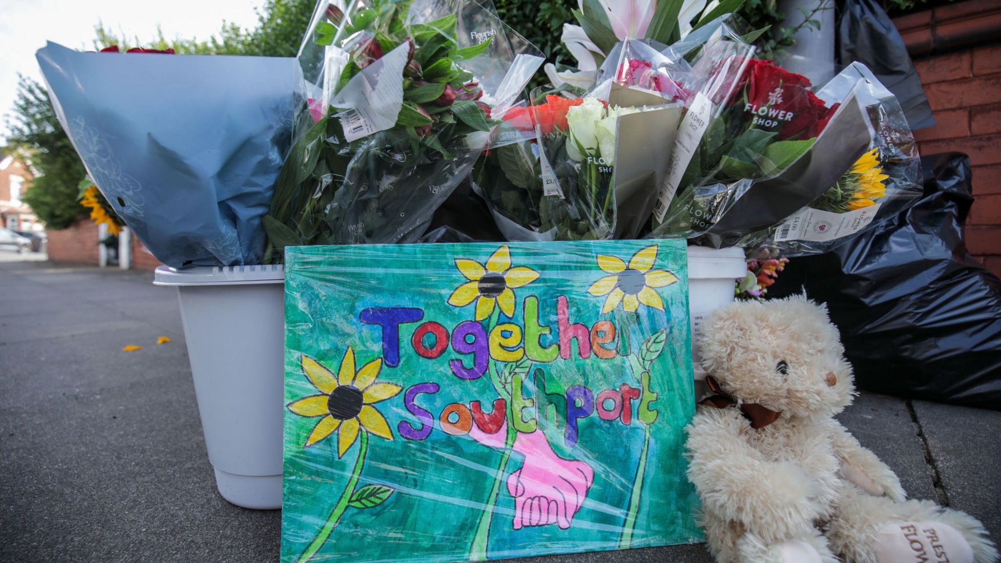 A sign which reads 'Together for Southport' next to a teddy 