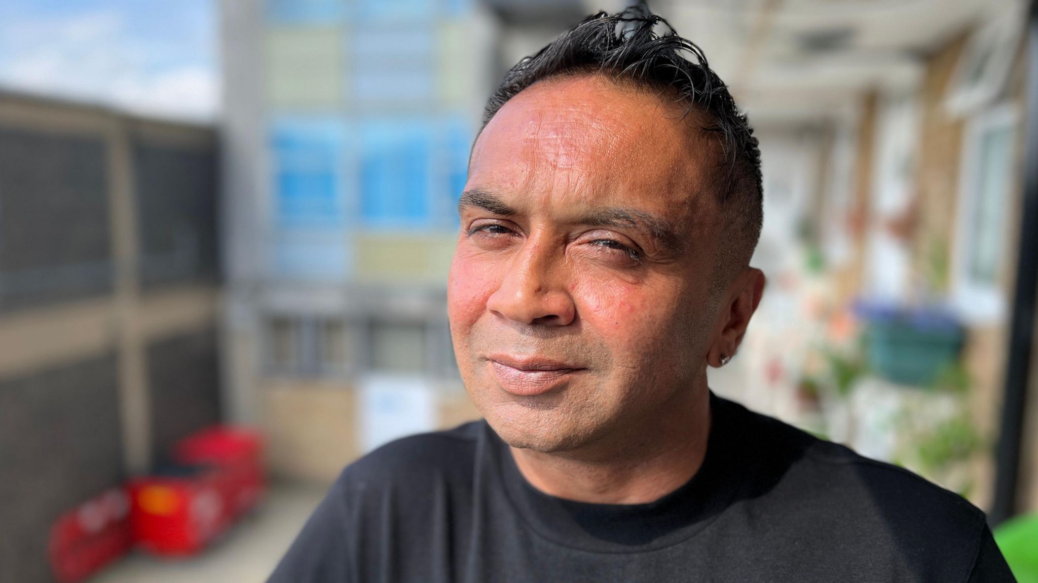 Sunjay Patel smiling and wearing a black t-shirt while standing on an outside 