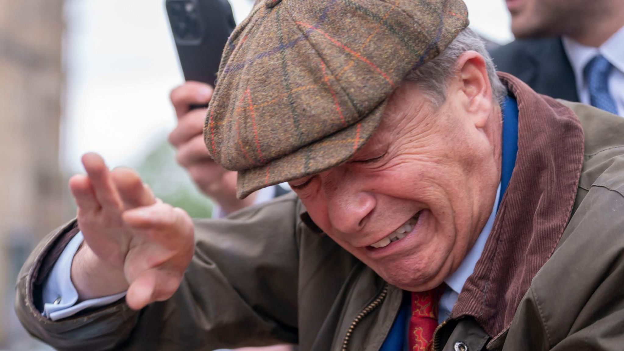 Nigel Farage holds his hand in front of his face