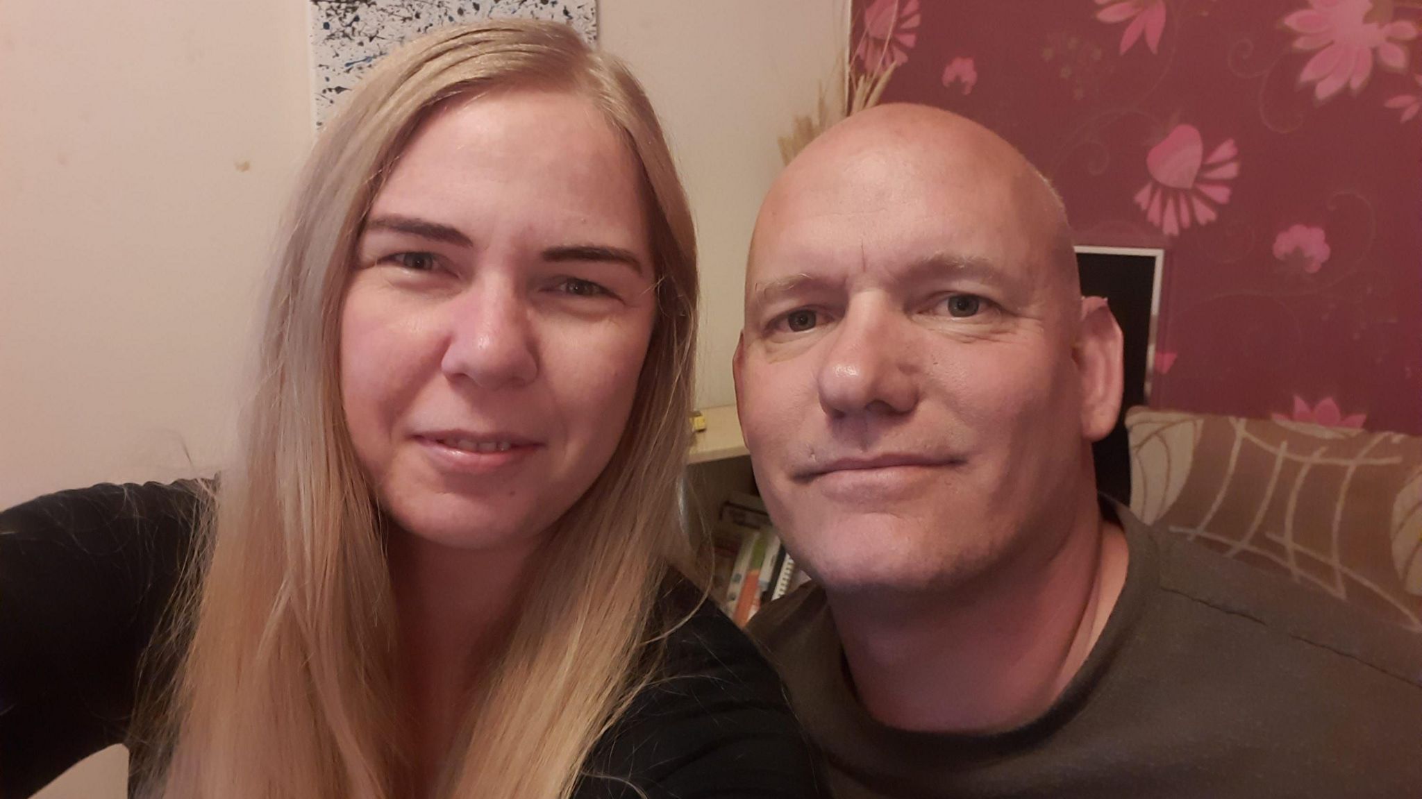 Veronika Mike and Zoltan Pinter. Ms Mike has long, blonde hair past her shoulders and a black top. Mr Pinter has a brown T-shirt on and has a shaved head. They sit in the corner of what looks like a living room.