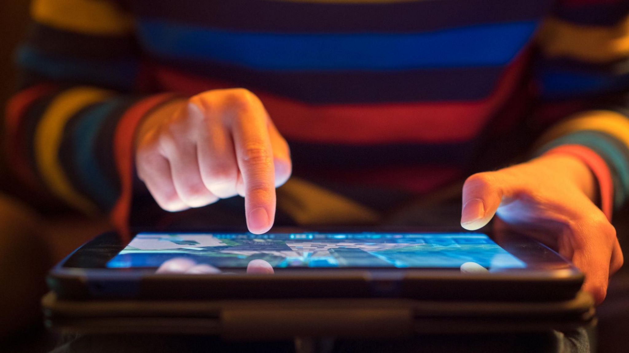 Man in striped jumper holding iPad