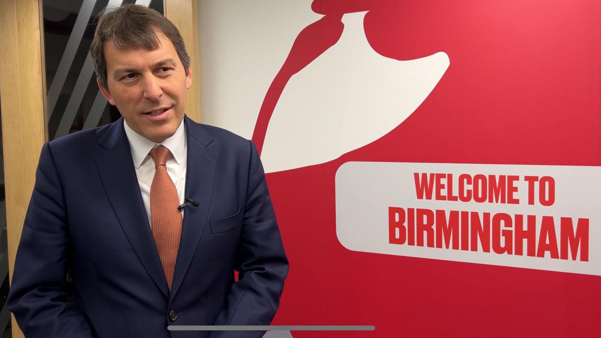 Cabinet Office Minister John Glen MP standing next to a "welcome to Birmingham" sign