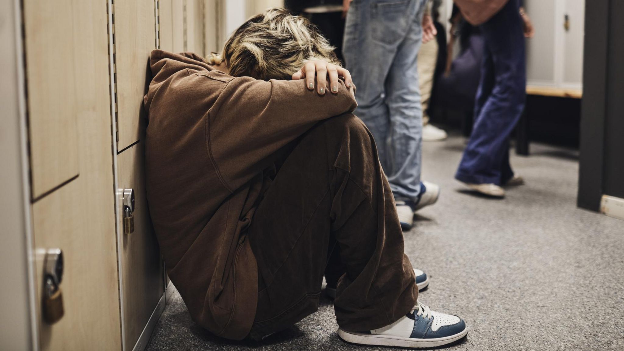 Un joven sentado en el suelo, con la cabeza entre las manos