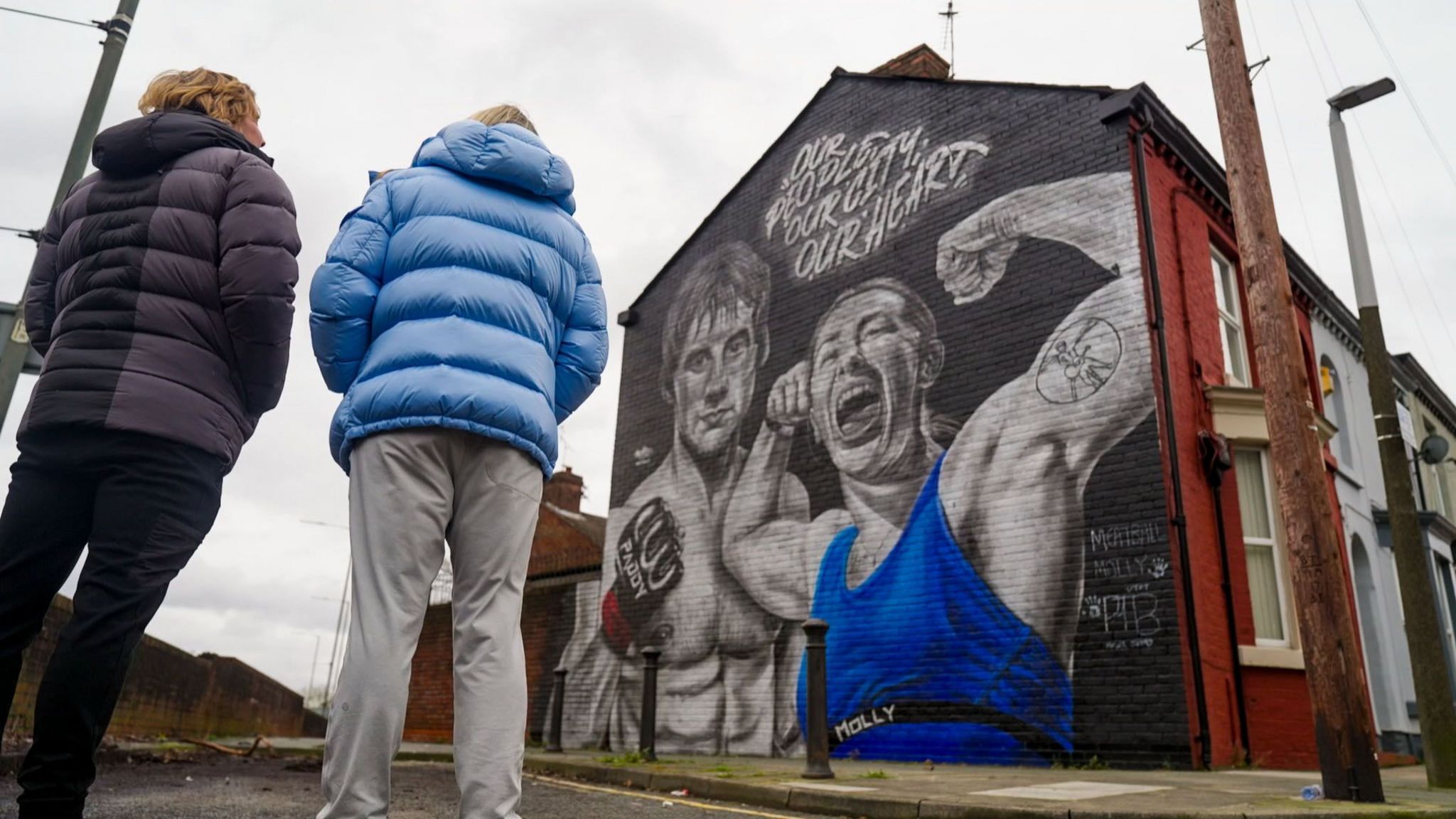 Molly McCann and Paddy Pimblett look at a mural in their honour.