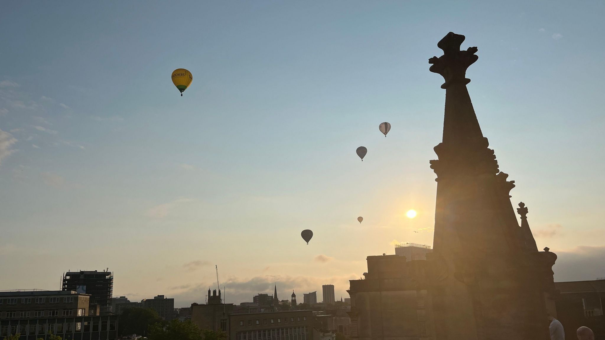 Five hot air balloons in the morning sky and a silhouette of the cathedral spires