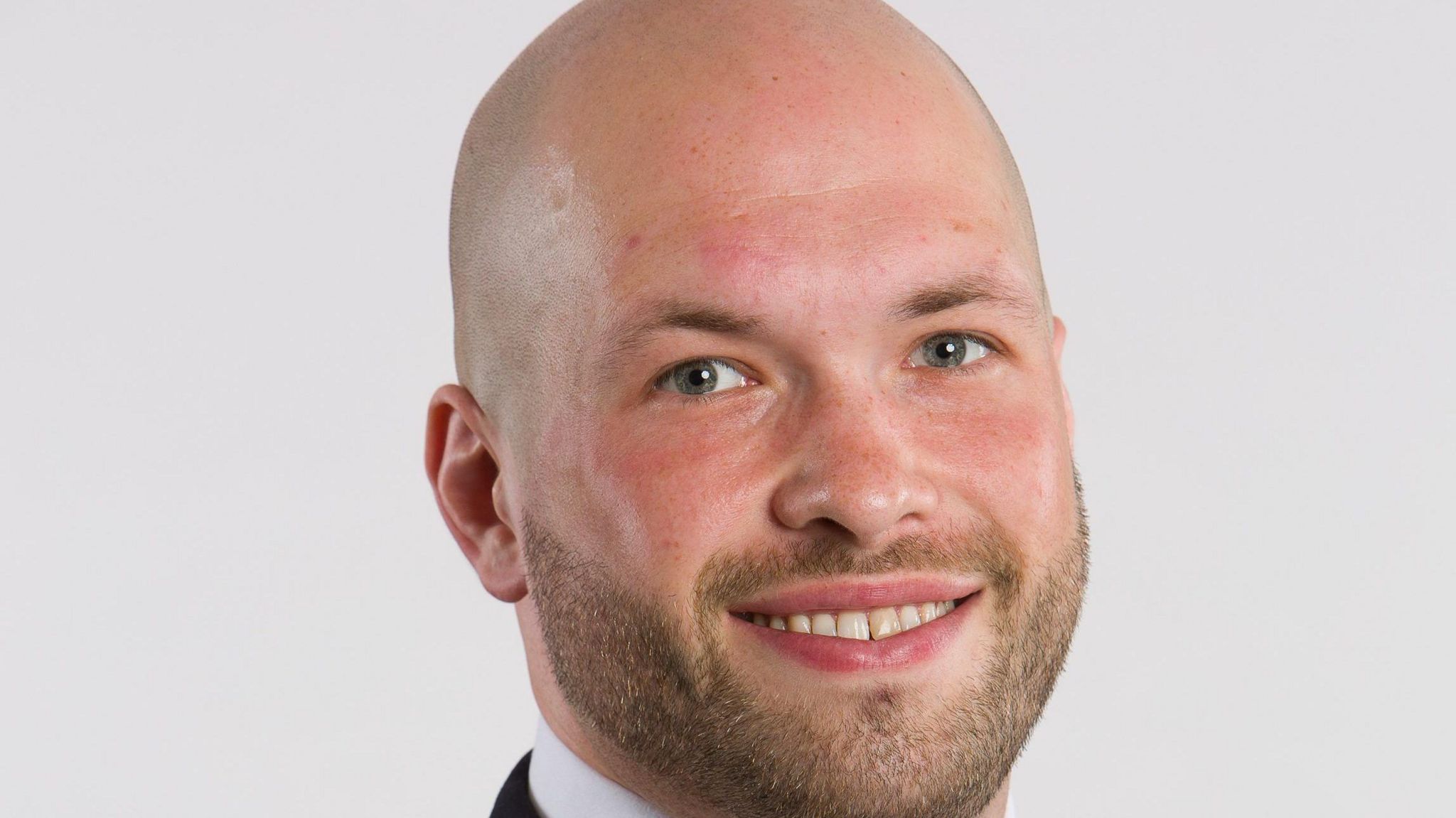 A headshot of Peter Lamb MP. He is wearing a suit and a read tie. He is smiling. 