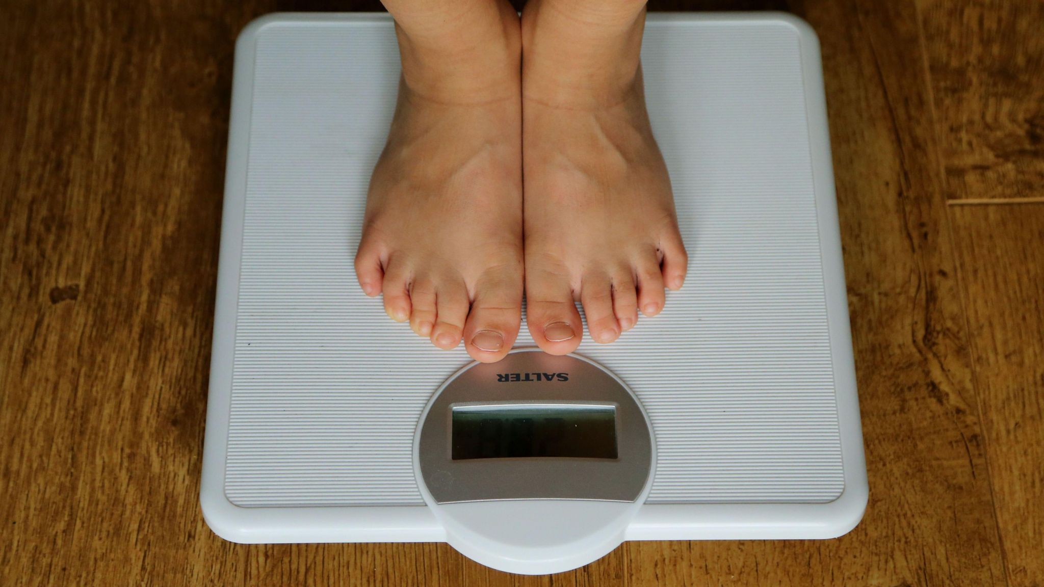 The feet of an anonymous person are shown standing on a set of scales