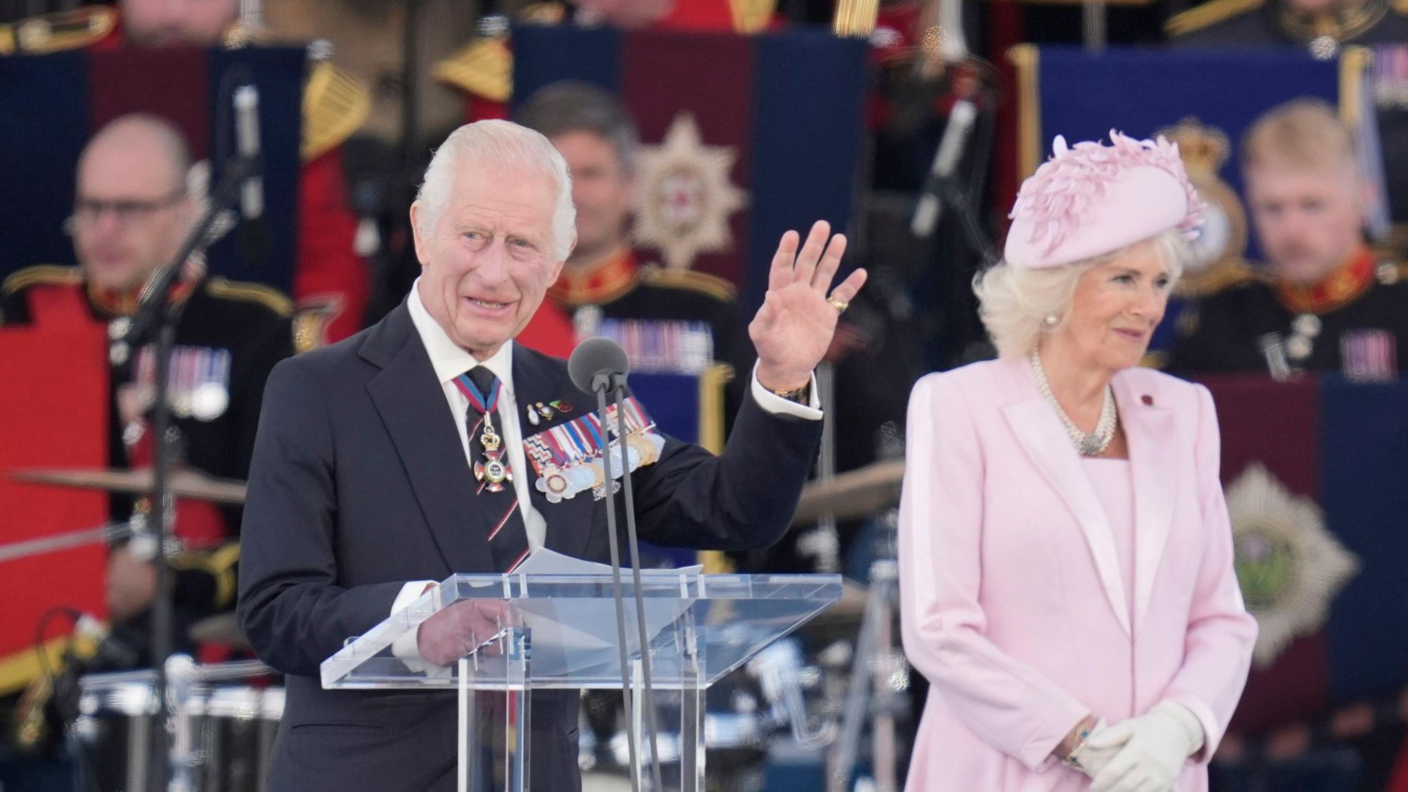 King Charles III and Queen Camilla on the stage at Southsea, the King can be seen waving as he is talking to the audience