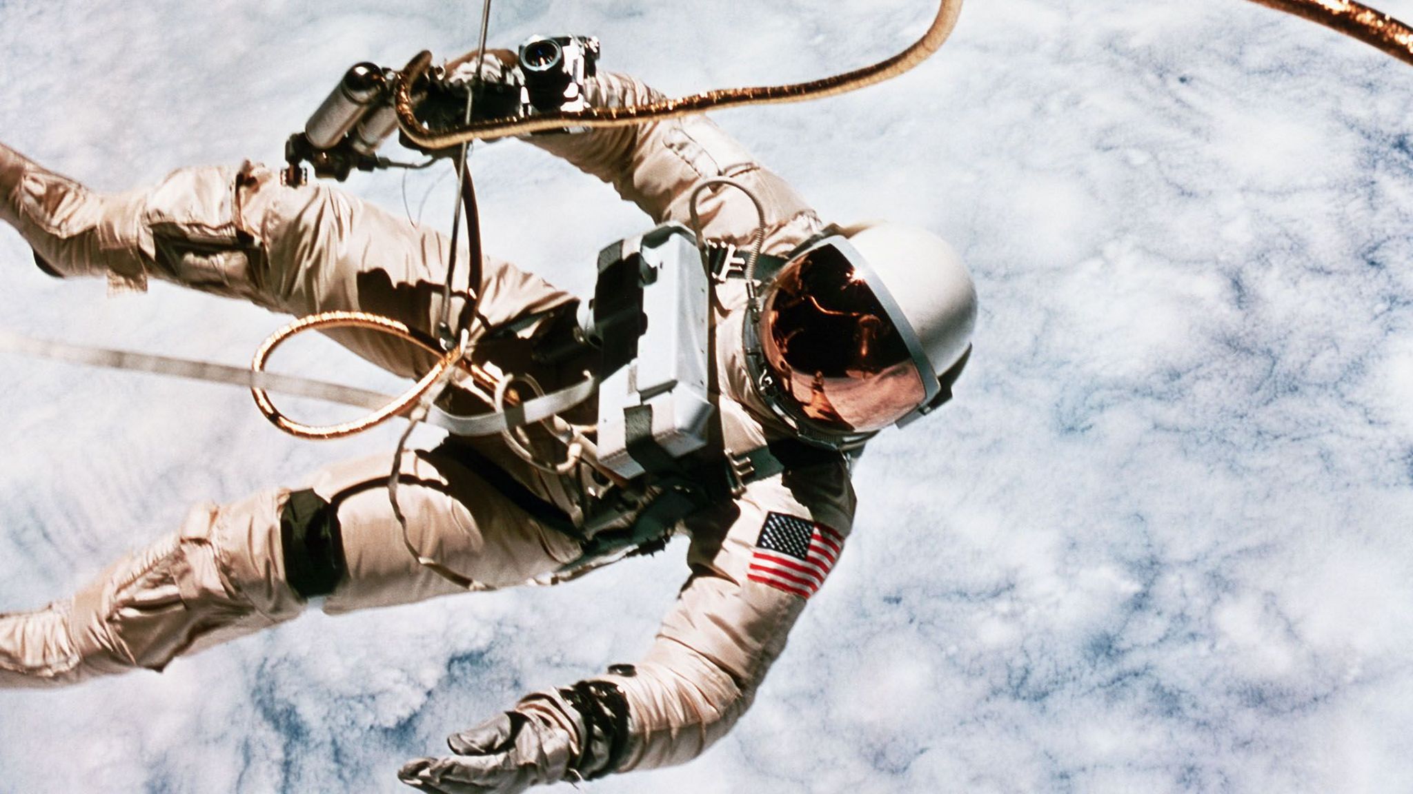 Ed White in his spacesuit performing a spacewalk above the clouds of the Earth